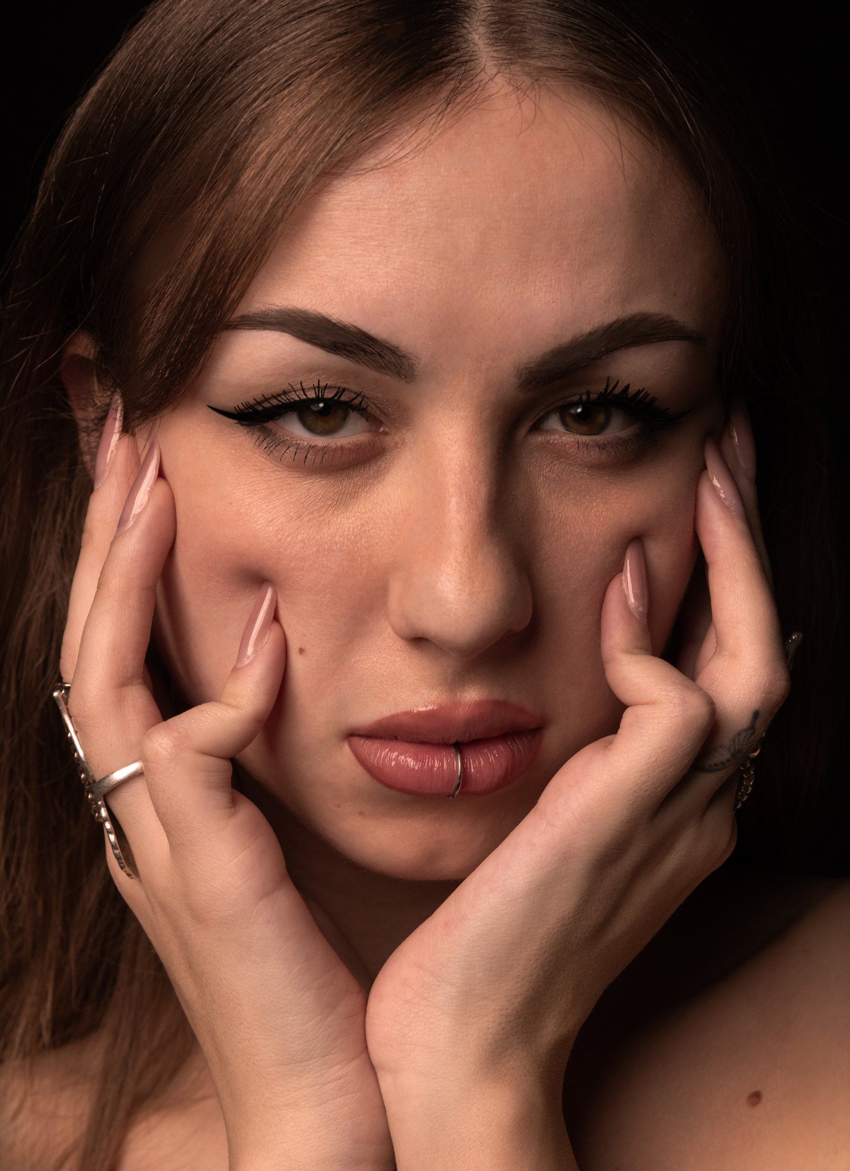 Ritratto a colori: mani sul viso, eyeliner grafico